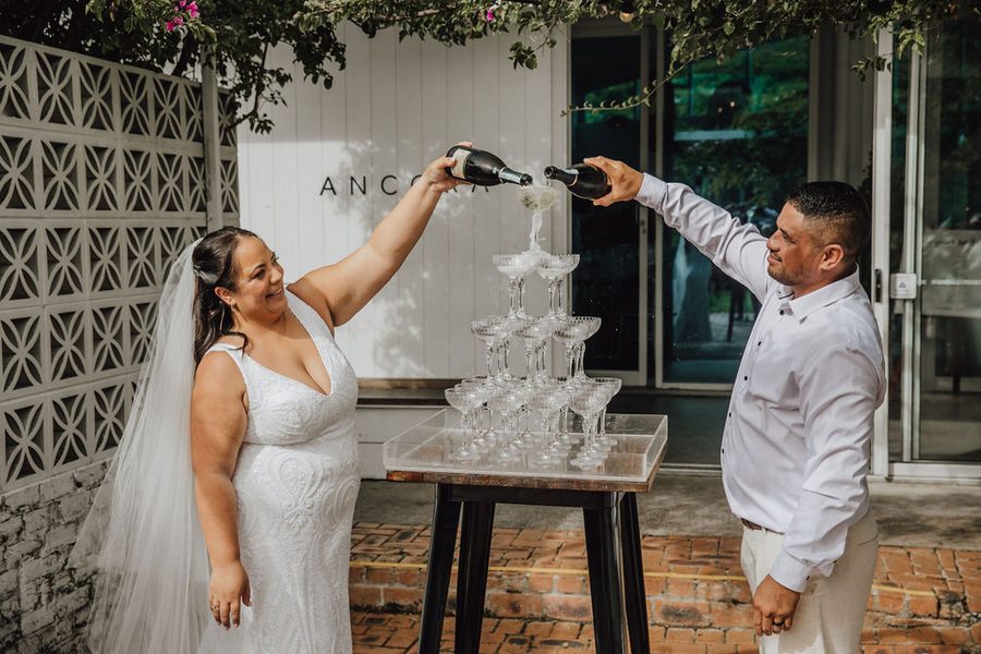 A Maori couple fill their champagne tower during their NZ Wedding at Ancora on the Gold Coast