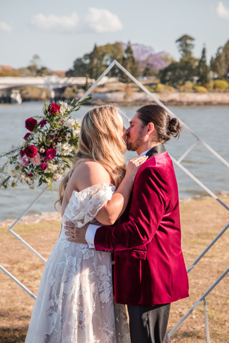 A couple kissing at beneath a wedding arbor