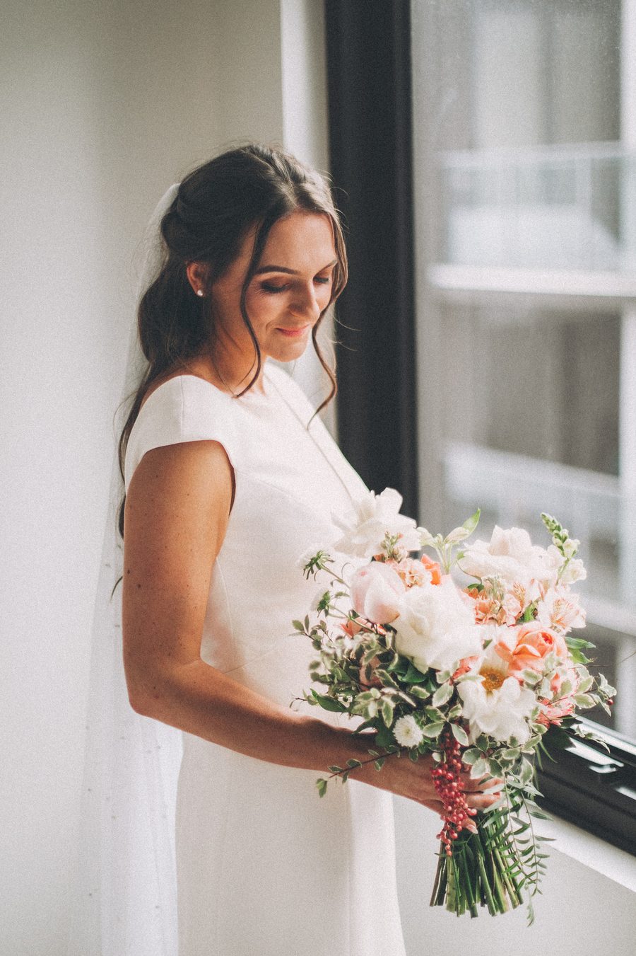 A Bride admiring her beautiful peach inspired wedding bouquet